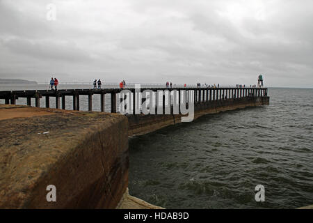 Whitby harbour parete e gente che cammina Foto Stock