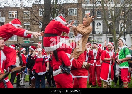 Londra, Regno Unito. Il 10 dicembre 2016. La North London Santacon in pausa nel parco al Mornington Crescent e alcuni hanno preso parte ad alcune giostre informale. Molti sacchetti trasportati con le lattine di birra o di bottiglie di vino che hanno bevuto sul percorso e si ferma dove hanno cantato e ballato e jousted, con l'occasionale germoglio di Bruxelles lotta tra babbo natale e gli elfi. Credito: Peter Marshall / Alamy Live News Foto Stock