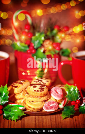 Tavola di natale di dolci, gustosi biscotti di panpepato decorate con bacche di santo e candy canes sul tavolo, tradizionale considera per Babbo Natale Foto Stock