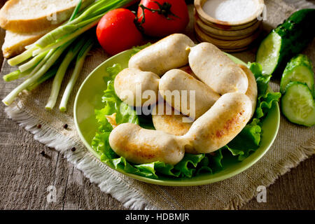 In casa la salsiccia di pollo e carne varie verdure, erbe su sfondo rustico. Foto Stock