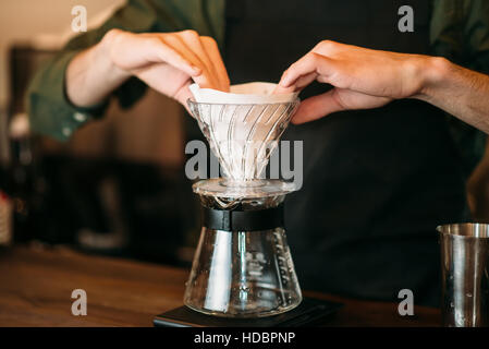 Primo piano delle mani maschio prepara il caffè in piedi sul bancone. Foto Stock