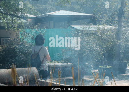 Una donna nel pensiero o di preghiera tra i bastoncini di incenso vicino al santuario principale Monastero Po Lin Lantau Island Hong Kong Asia Foto Stock