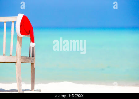 Santa Claus Hat su una sedia vicino a spiaggia tropicale con acqua del mare turchese e la sabbia bianca. Vacanze di Natale concept Foto Stock