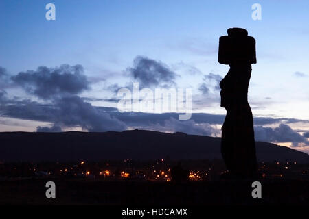 Antico moai a Ahu Tahai affacciato di notte le luci della moderna Hanga Roa città sull isola di pasqua. Foto Stock