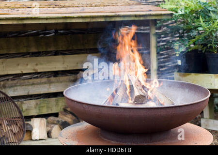 Una buca per il fuoco da una tettoia in legno in un giardino Foto Stock