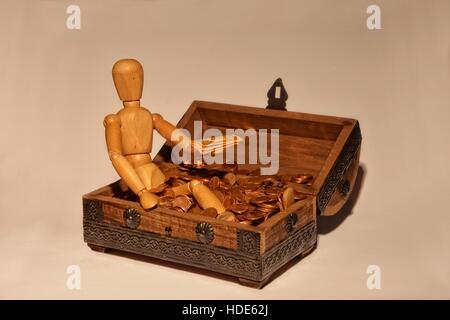 Figura in legno seduta in una scatola di legno con denaro, bill per la mano Foto Stock