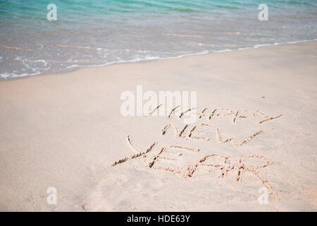 Felice Anno Nuovo scritto nella sabbia bianca Foto Stock