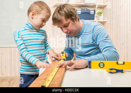 Ragazzo aiuta il padre nel lavoro del falegname Foto Stock