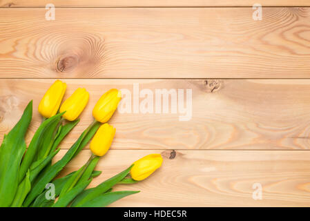 Cinque tulipani gialli su assi di legno in un angolo Foto Stock