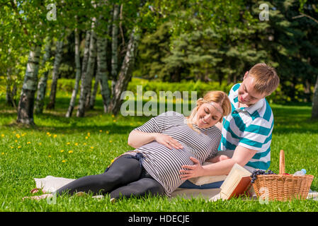 Una donna e un uomo di trascorrere il loro tempo libero al picnic, la donna è in stato di gravidanza Foto Stock
