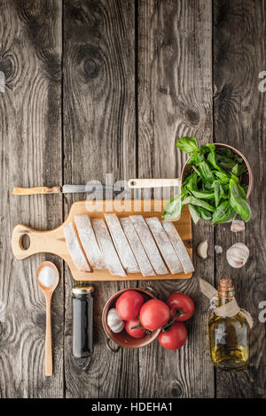 Ingredienti per la bruschetta sul tavolo di legno in verticale Foto Stock