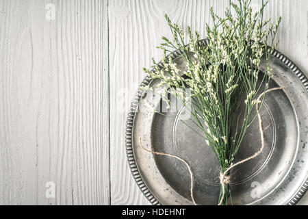 Fiori in la piastra metallica sul bianco tavolo in legno vista superiore Foto Stock