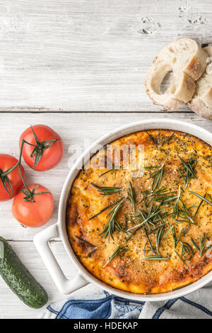 La Moussaka nel tavolo bianco con verdura e pane in verticale Foto Stock