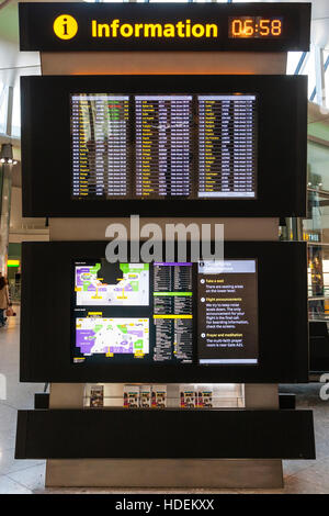 Inghilterra, London, Aereoporto di Heathrow, terminale 2. Partenza lounge interior. Partenze stand informativo e display, che mostra i numeri di porta. 6:58. Foto Stock