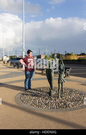 Giovane uomo sulla Esplenade, Fleetwood, visualizzazione la scultura "Benvenuti a casa" di Anita Lafford. Foto Stock