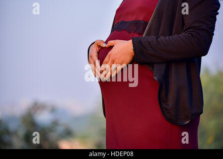La maternità scatta di un ottavo mese di gravidanza della donna che indossa un bel vestito in una posizione esterna Foto Stock