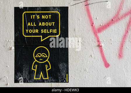 Street Art poster appeso al muro bianco da artista SUBDUDE con uomo stilizzato e fumetti con slogan "Non è tutto circa il vostro selfie' Foto Stock