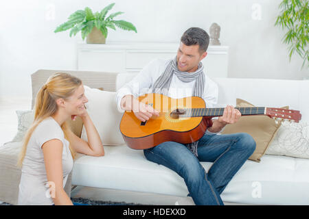 Uomo a suonare la chitarra per signora Foto Stock