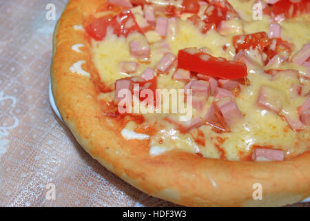 Una gustosa pizza con un appetitoso ripieno di formaggio salsiccia e pomodori Foto Stock