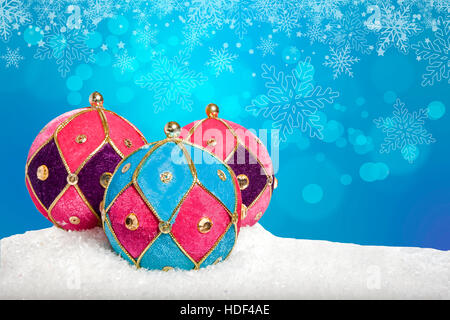 Colourful Christmas baubles on snow Foto Stock