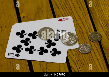 2 carte (Ace e 10) da una riproduzione standard deck su un tavolo di legno con Singapore delle monete in valuta Foto Stock