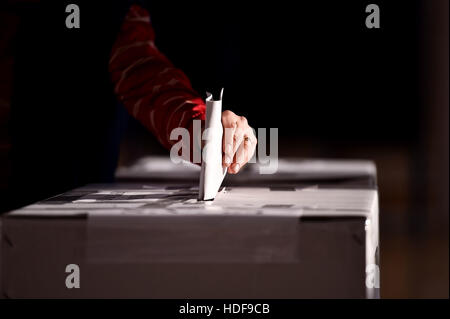 La mano di una persona la colata di una votazione in urne durante le elezioni Foto Stock