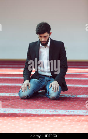 Giovane uomo musulmano in preghiera nella moschea colorati Foto Stock