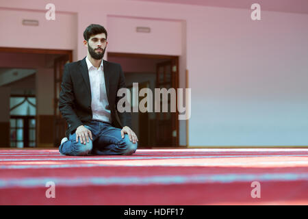 Giovane uomo musulmano in preghiera nella moschea colorati Foto Stock