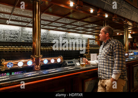 Uomo che tiene un bicchiere di birra al Ølhallen, il più antico pub di Tromso, Troms, Norvegia Foto Stock