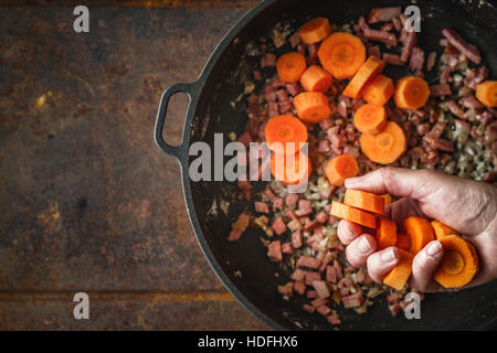 Aggiungere le carote in padella con pancetta vista superiore Foto Stock