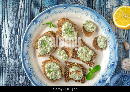 Piastra con diverse fette di pane con tzatziki sul tavolo blu vista superiore Foto Stock