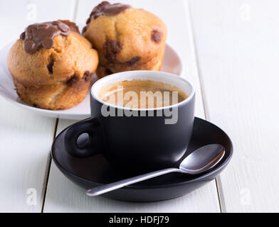 Caffè del mattino in Coppa del nero su sfondo bianco con dei pirottini di dietro. Foto Stock