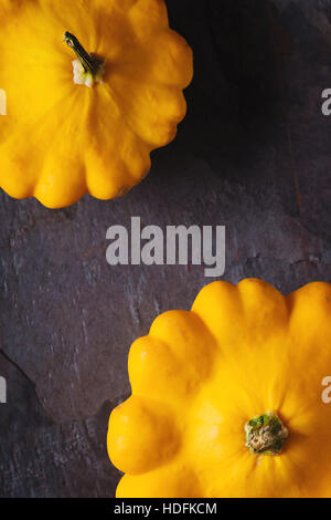 Giallo zucca freschi patty pan sulla pietra scura verticale di sfondo Foto Stock