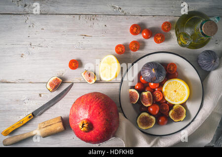 Ingredienti per insalata di frutta con pomodori sul bianco tavolo in legno Foto Stock