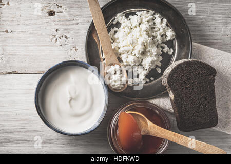 Cottage fresco formaggio con panna acida e marmellata e pane sul bianco tavolo in legno vista superiore Foto Stock