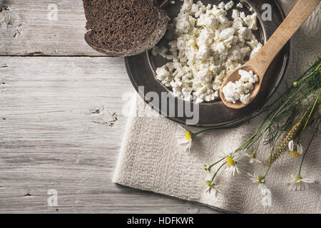 Fresco formaggio cottage con pane e fiori sul bianco tavolo in legno vista superiore Foto Stock