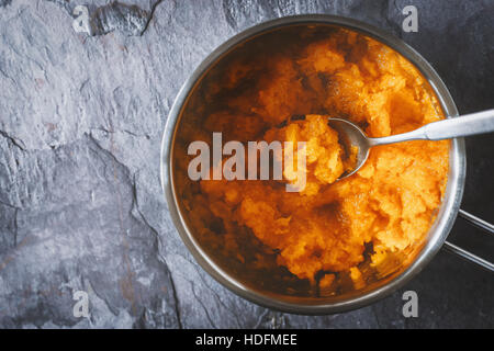 Purea di zucca in pentola con cucchiaio in background in pietra vista superiore Foto Stock