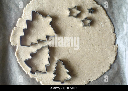 Natale cookie cutters sull'impasto crudo sulla pergamena vista superiore Foto Stock