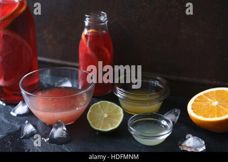 Cocktail di agrumi in diversi piatto di vetro sulla pietra scura sullo sfondo Foto Stock