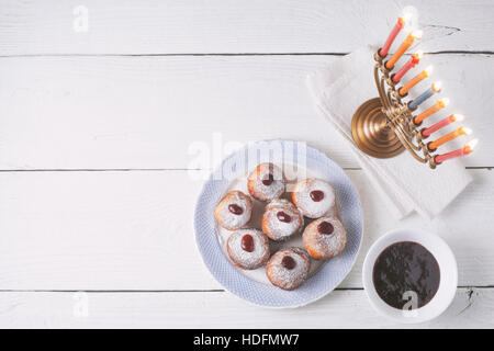 Hanukkah menorah e sufganiot sul bianco tavolo in legno vista superiore Foto Stock