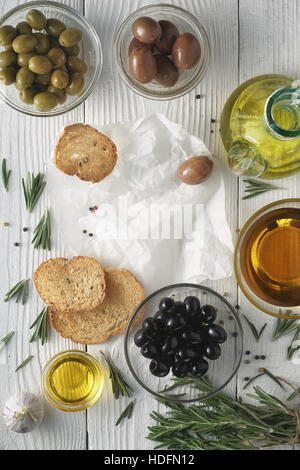 Olio di oliva con pane e Olive mix sul legno bianco verticale della tabella Foto Stock