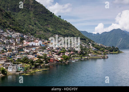 Vista in lontananza San Antonio Palopo, Guatemala, sulla riva del lago Atitlan. I ripidi pendii in discesa al lago, che è un extinict cratere vulcanico Foto Stock