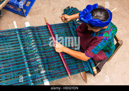 Una donna Maya in abito tradizionale tesse tessuto su un telaio posteriore in Santa Cruz la Laguna, Guatemala. Vista aerea. Foto Stock