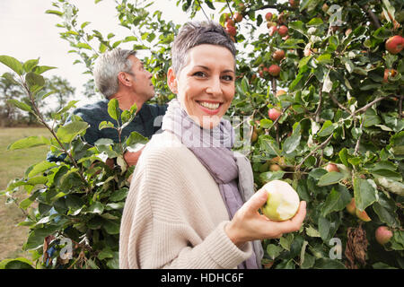 Ritratto di donna felice di mangiare in apple Orchard Foto Stock