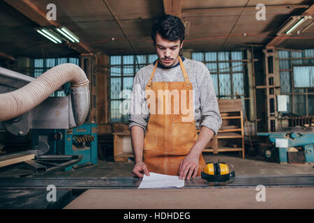 Falegname documento di lettura sul banco di lavoro in officina Foto Stock