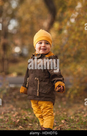 Sorridente baby boy guardando lontano rimanendo in posizione di parcheggio durante l'autunno Foto Stock