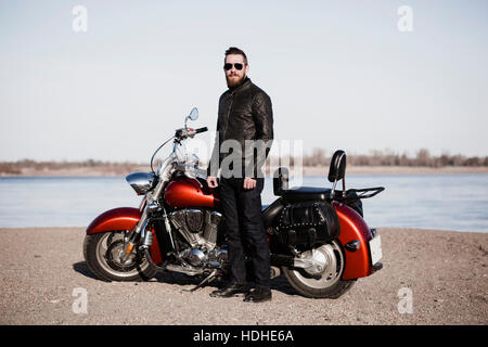 A piena lunghezza Ritratto di biker in piedi in moto sul lungolago Foto Stock