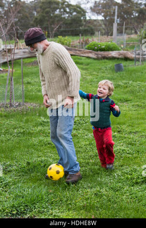 Per tutta la lunghezza del nonno e nipote che giocano a calcio sul campo erboso Foto Stock