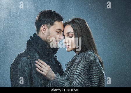 Coppia romantica in abiti caldi in piedi contro lo sfondo grigio Foto Stock