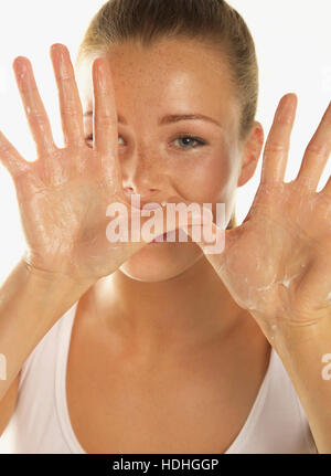 Close-up ritratto di donna bella mostra body lotion sui palmi delle mani contro uno sfondo bianco Foto Stock